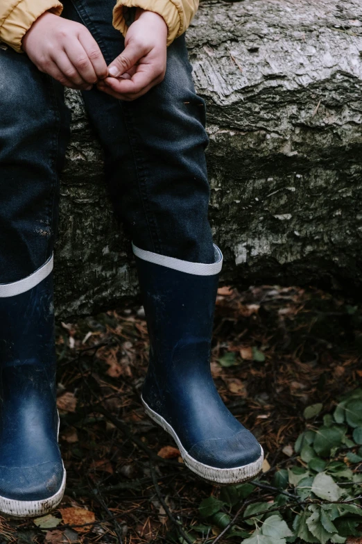 a young child in jeans is holding hands with his feet