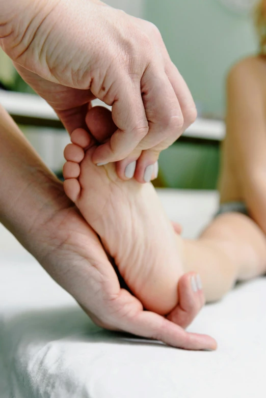 a close up of a person holding their feet while lying on a bed