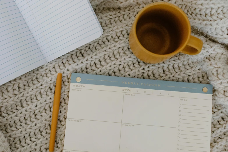 notebook with pen, coffee mug and notepad on the floor