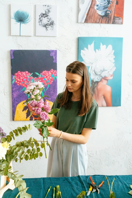 woman in green top arranging flowers in studio setting