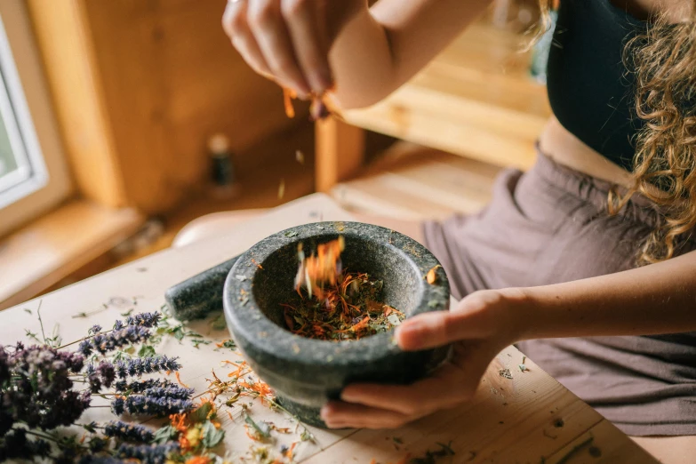a woman with a pot is stirring a fire
