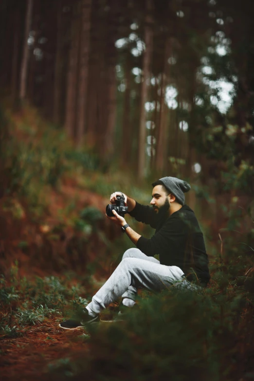 a man with a camera taking a selfie in the woods