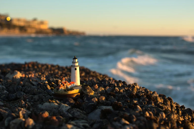 a lighthouse stands on rocks near a rough ocean