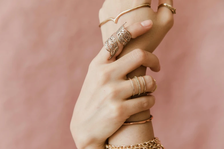 two hands are holding gold colored jewelry and chains