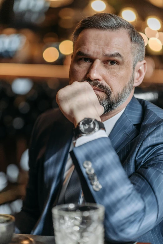 a man with a goatee and beard wearing a suit sitting in a restaurant