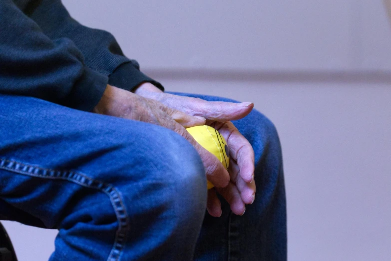 a man holding a yellow ball sits in his hands