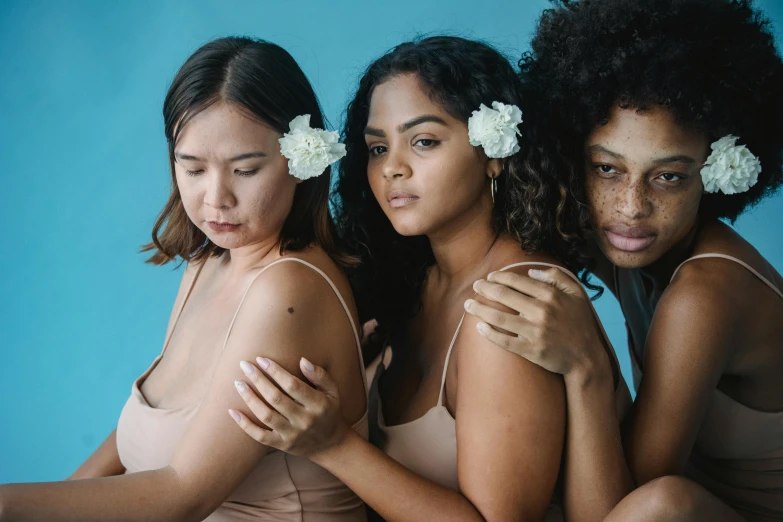 three women are wearing  bodysuits with flower clips