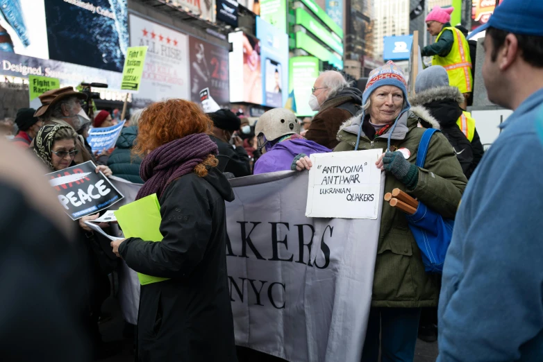 a group of people stand on the sidewalk and hold signs