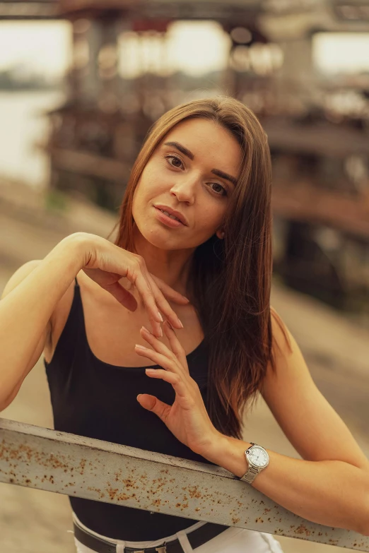 a beautiful young lady leaning on a rail near the ocean