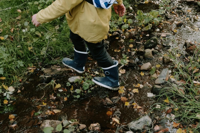 a person wearing rain boots walking down a small path