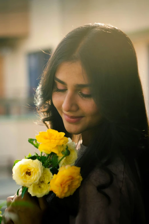 a woman with long hair and a brown shirt holds a bunch of flowers