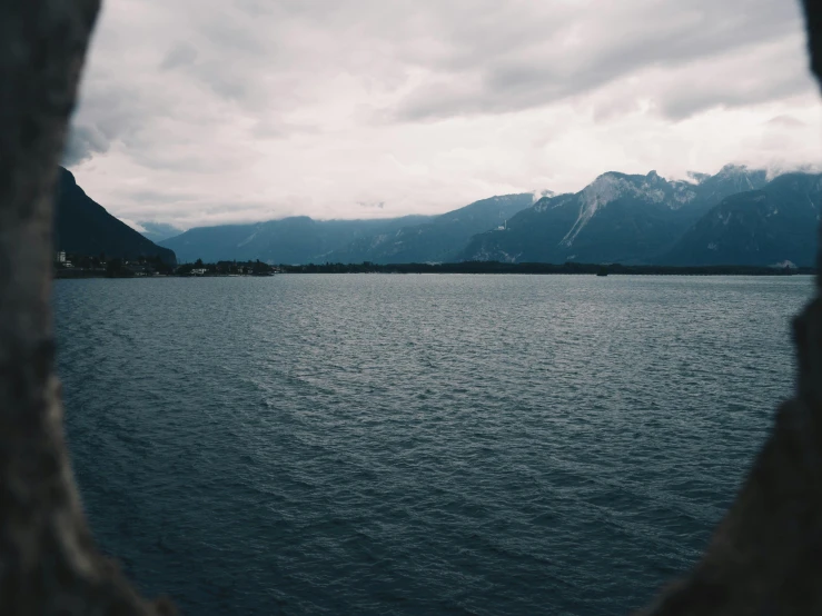 a body of water sitting next to mountains under a cloudy sky