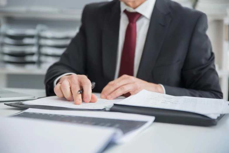 a businessman in a suit is taking notes while he sits at a desk