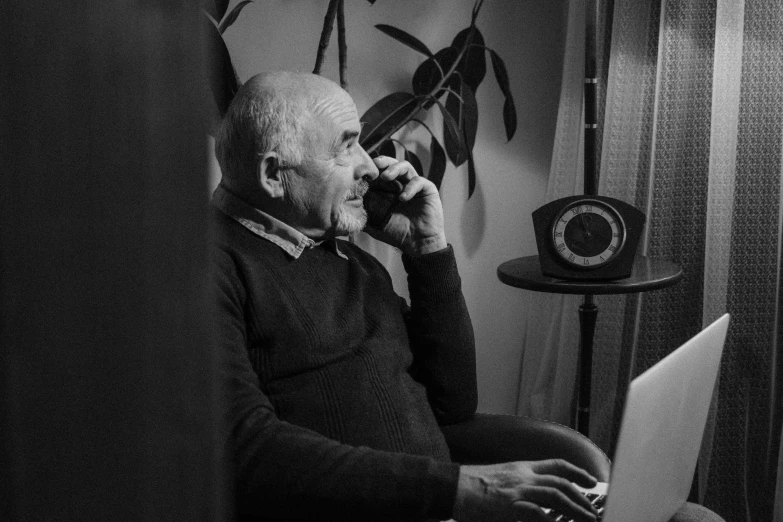 a man sitting in a chair while talking on the phone