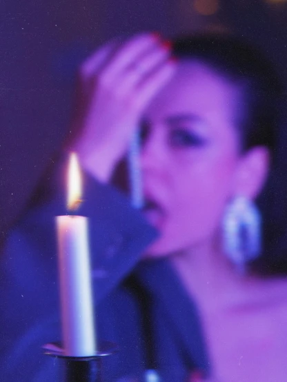 a woman looks at the bottom of a candle while in the dark