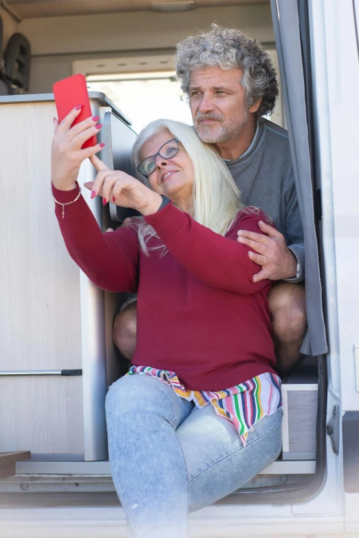 a woman taking a picture with her phone while sitting next to an older man