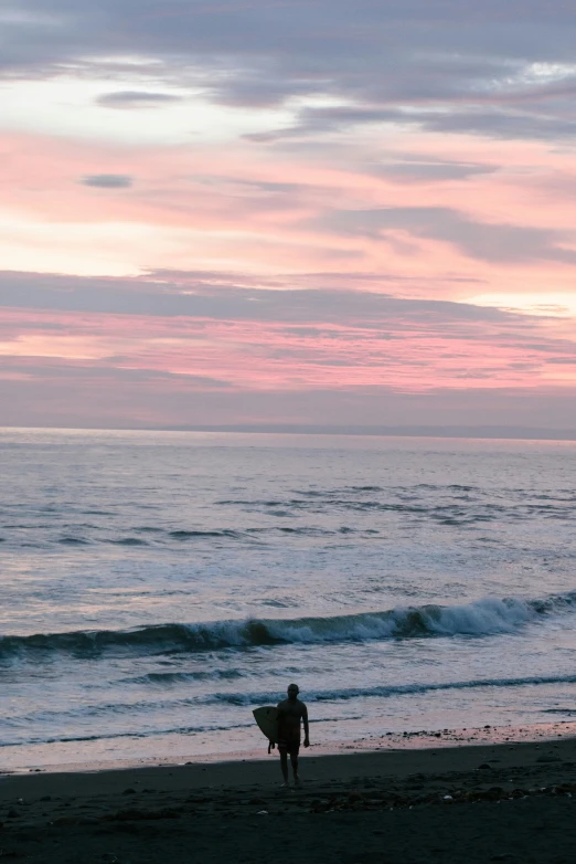 a person walking along a beach under a cloudy sky