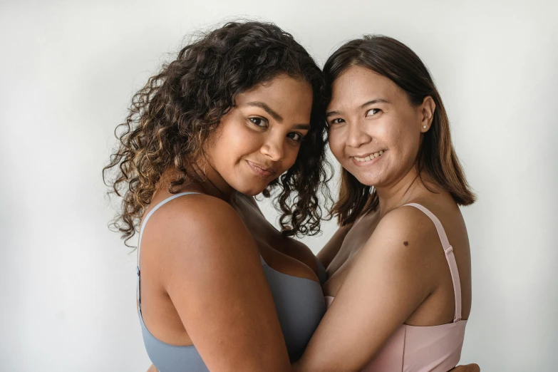 two women hugging each other in front of a white wall