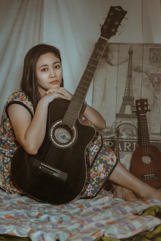 the girl is sitting on a bed and playing her guitar