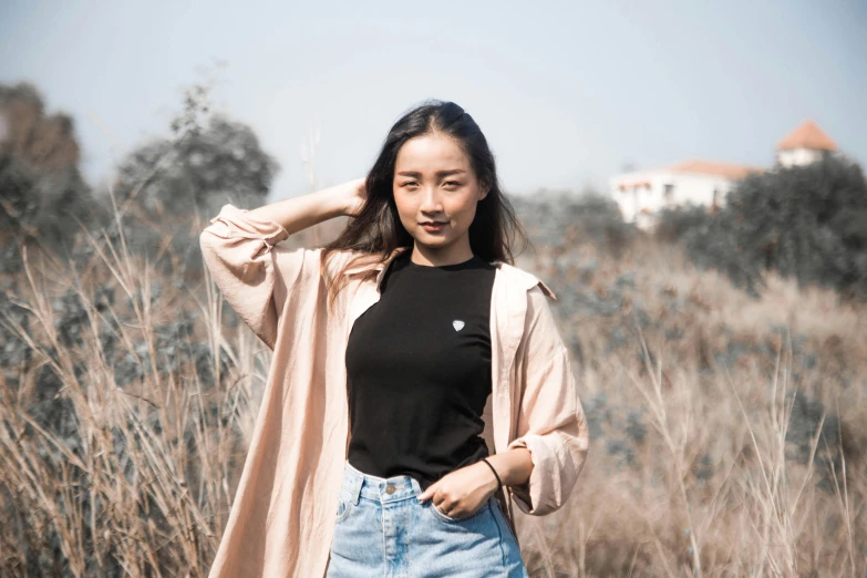 a woman standing in an open field wearing a black top