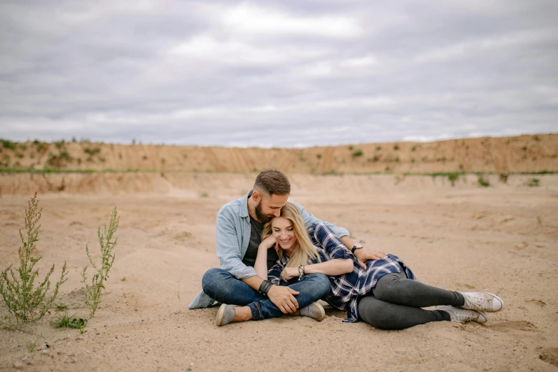 a man and woman on the sand, posing for a pograph