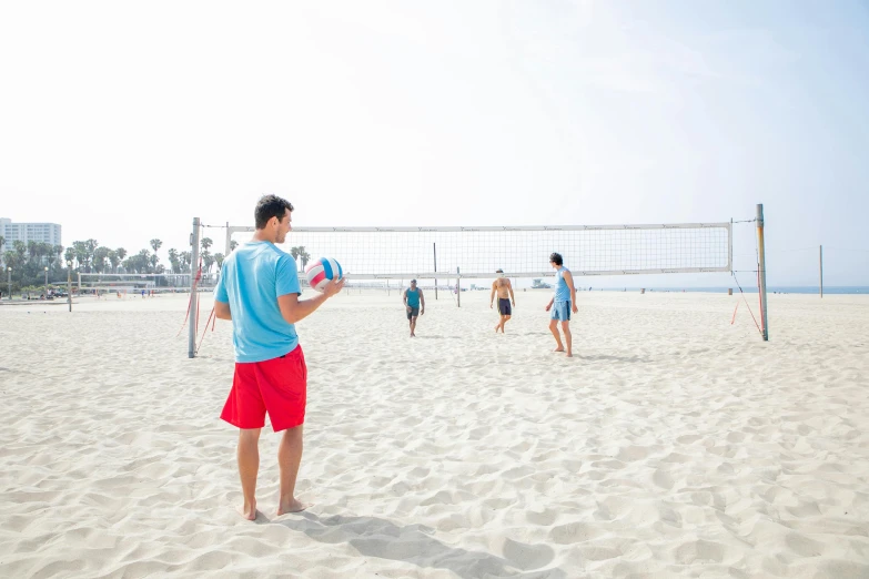 a man is standing on the sand playing volleyball
