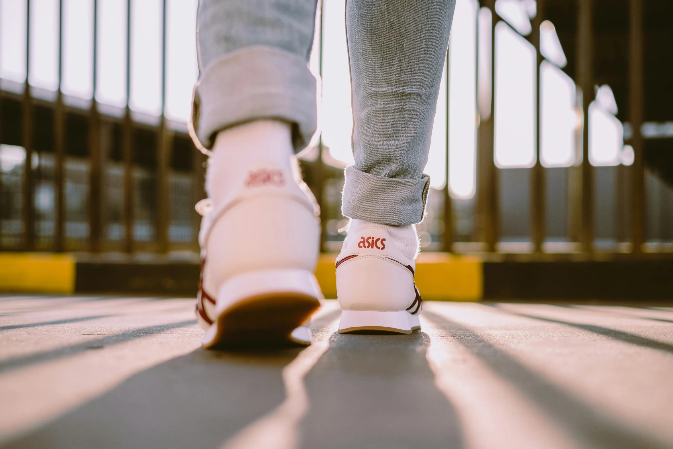 someone wearing white tennis shoes walking in an enclosed walkway