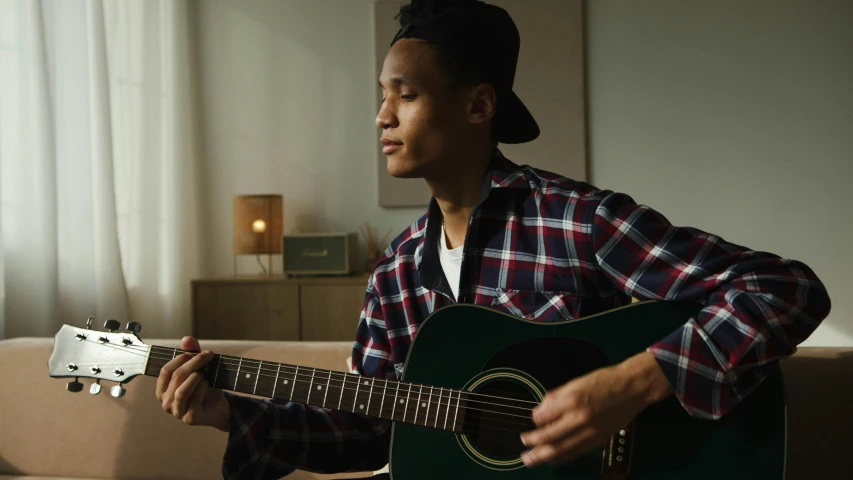 a man in plaid shirt playing the guitar