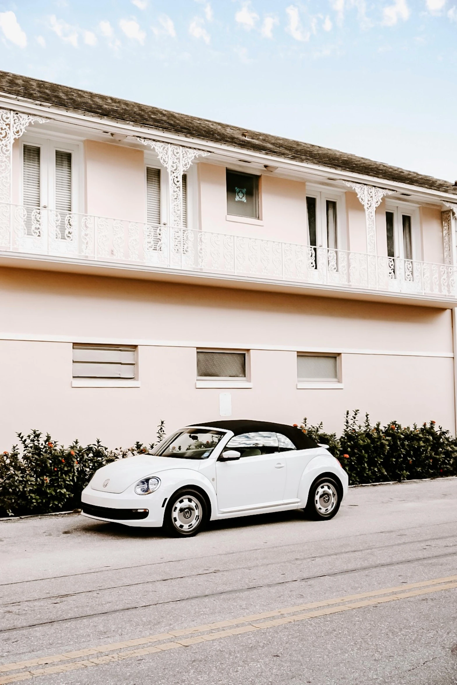 a white car parked in front of a pink building