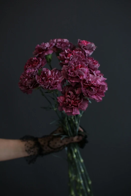 a hand holding up purple flowers in a vase