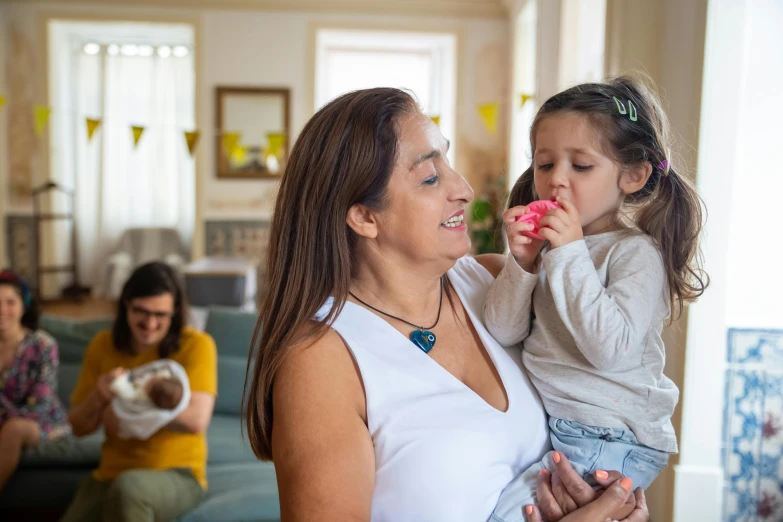 a woman holds her daughter while the child eats a donut