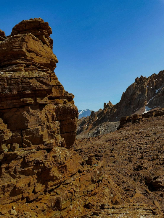 a large rock formation in the desert surrounded by some mountains