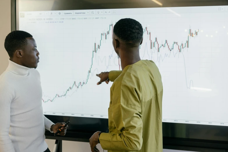 two people are talking next to a large board