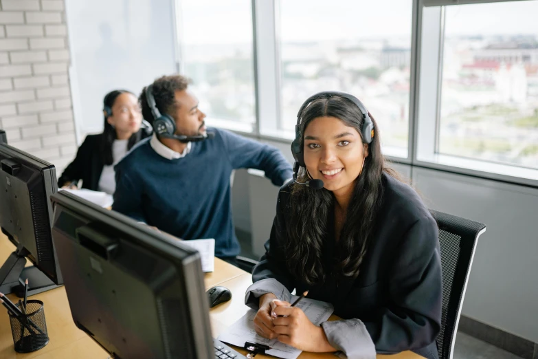 two people sit at computers smiling at the camera