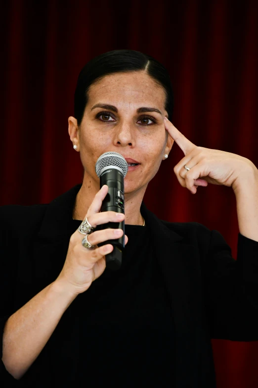 a woman holding a microphone and pointing with both hands