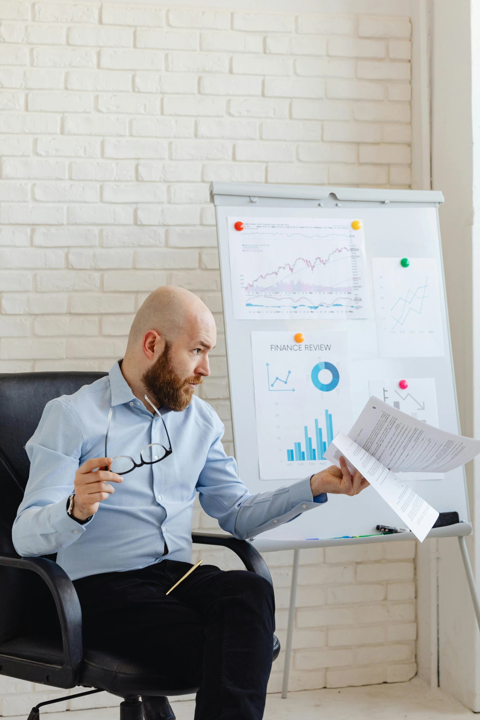 a man with a beard in a chair looking at a chart