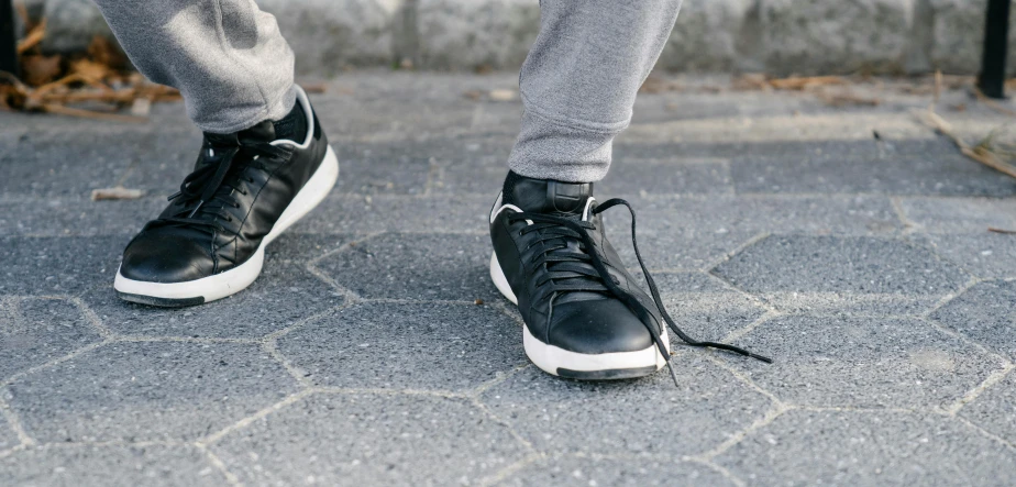 man in sneakers stepping on pavement with his feet hanging down