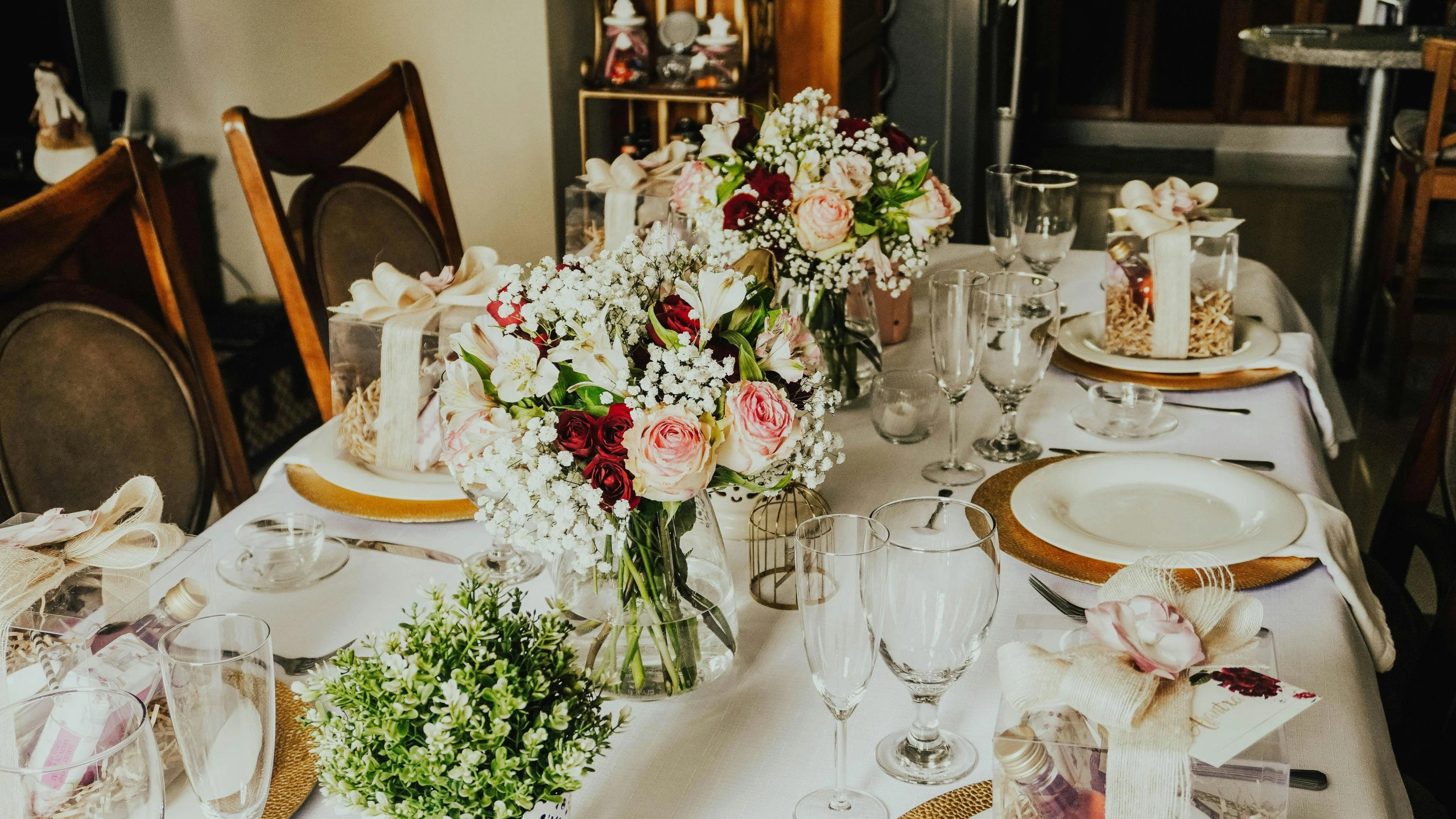 the table has several clear vases with flowers