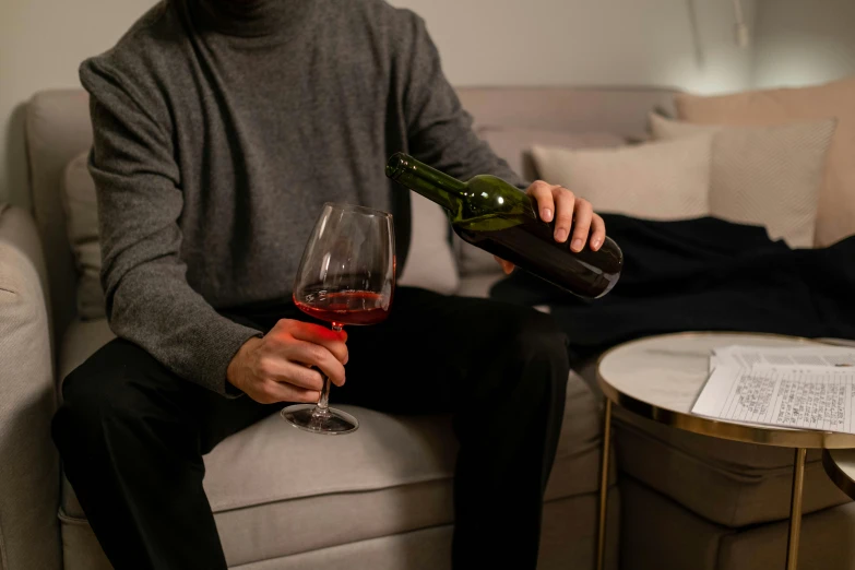 a man holding a glass of wine next to a table with paperwork on it