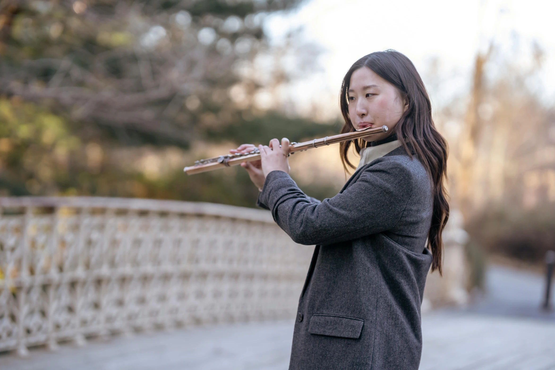 a woman is playing a flute while standing outside