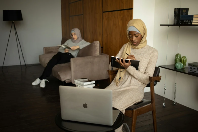 a woman sits on a chair in front of a laptop