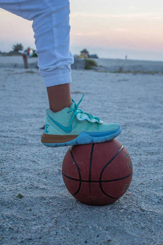 a person's feet on a basketball in a sandy area