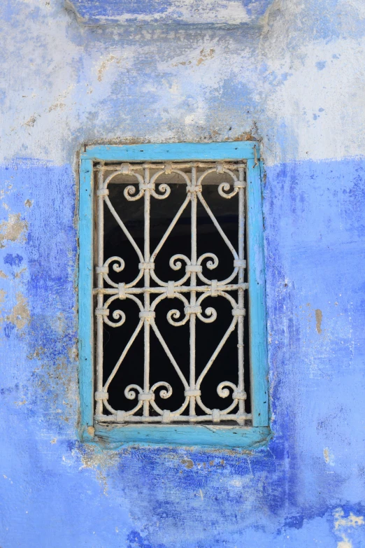 a blue wall with a window with iron bars