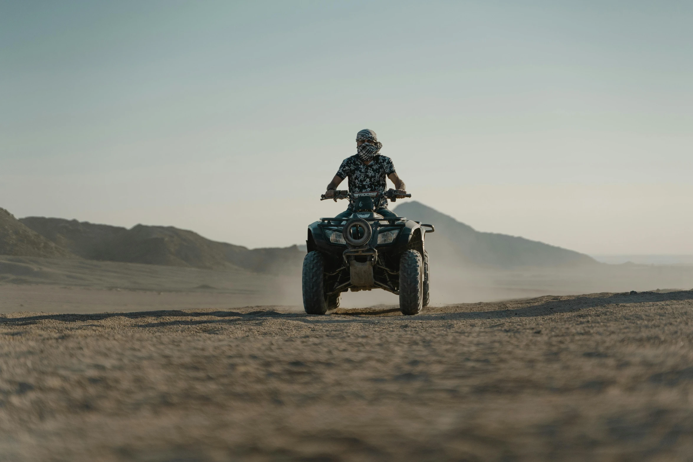 the man is riding on a four - wheeler on dirt