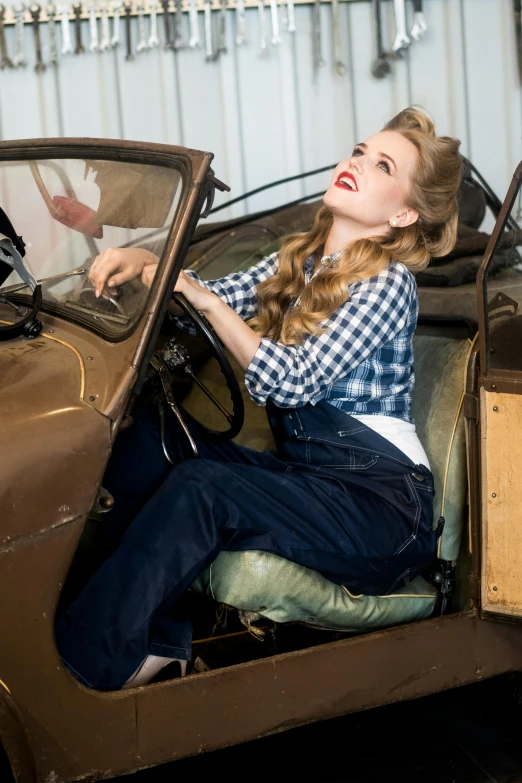 the woman is inside of the car with her hand on the steering wheel