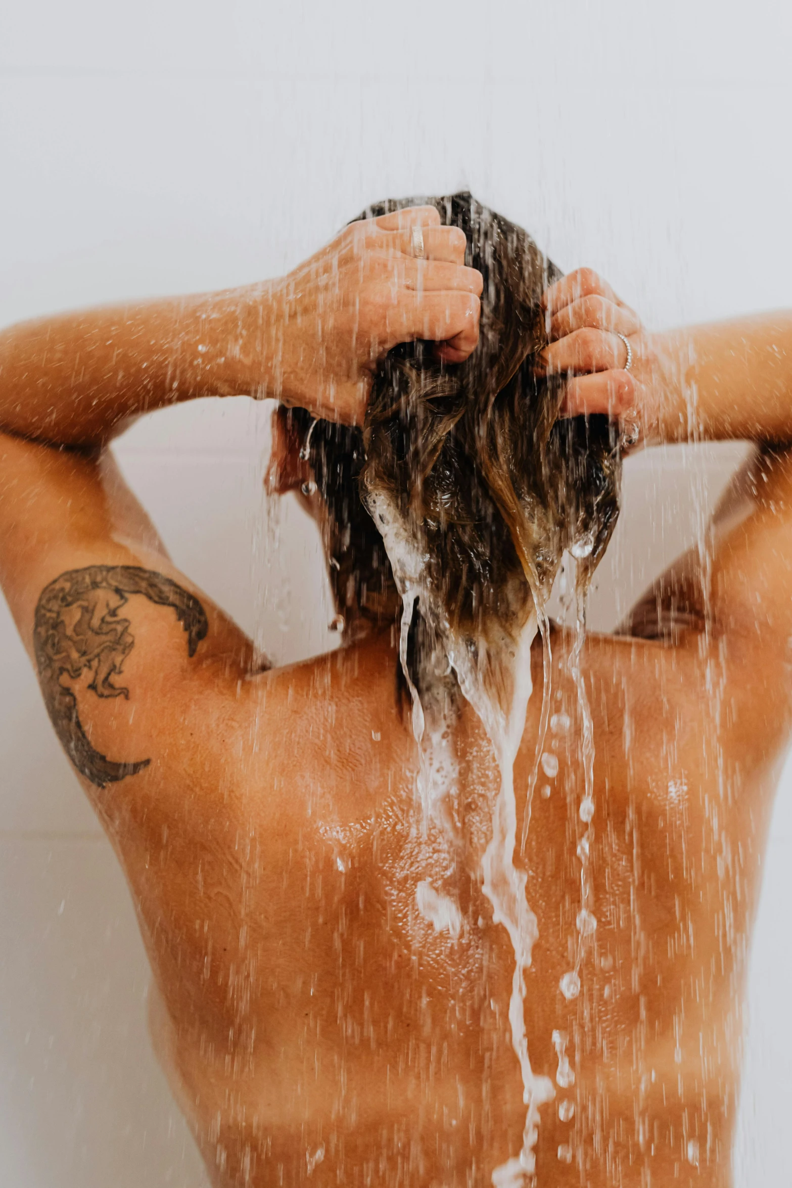 a person in the bath shower holding his hair back