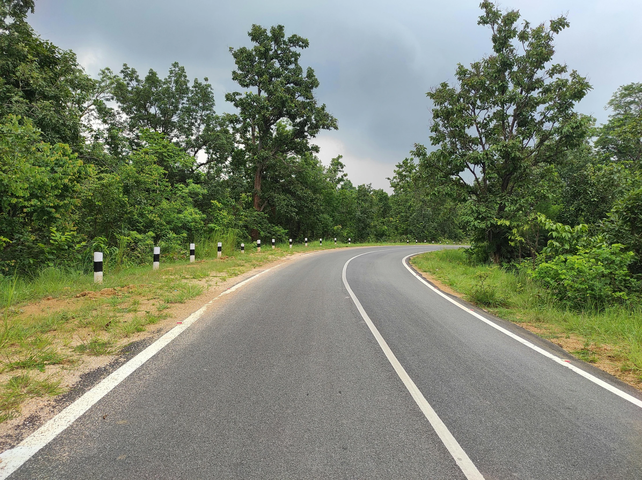 the road is curved into the direction and has a very low hill side