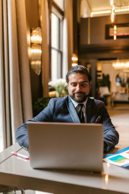 a man in a suit and tie sitting at a table with a laptop