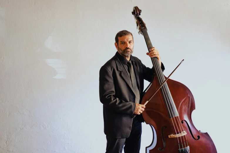 an older man in a suit and bow with the back of a cello