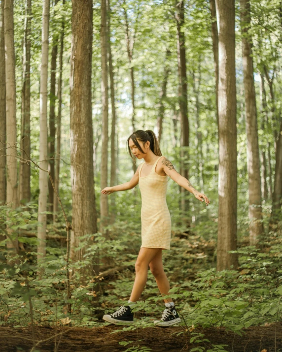 a young woman standing on a log in the woods